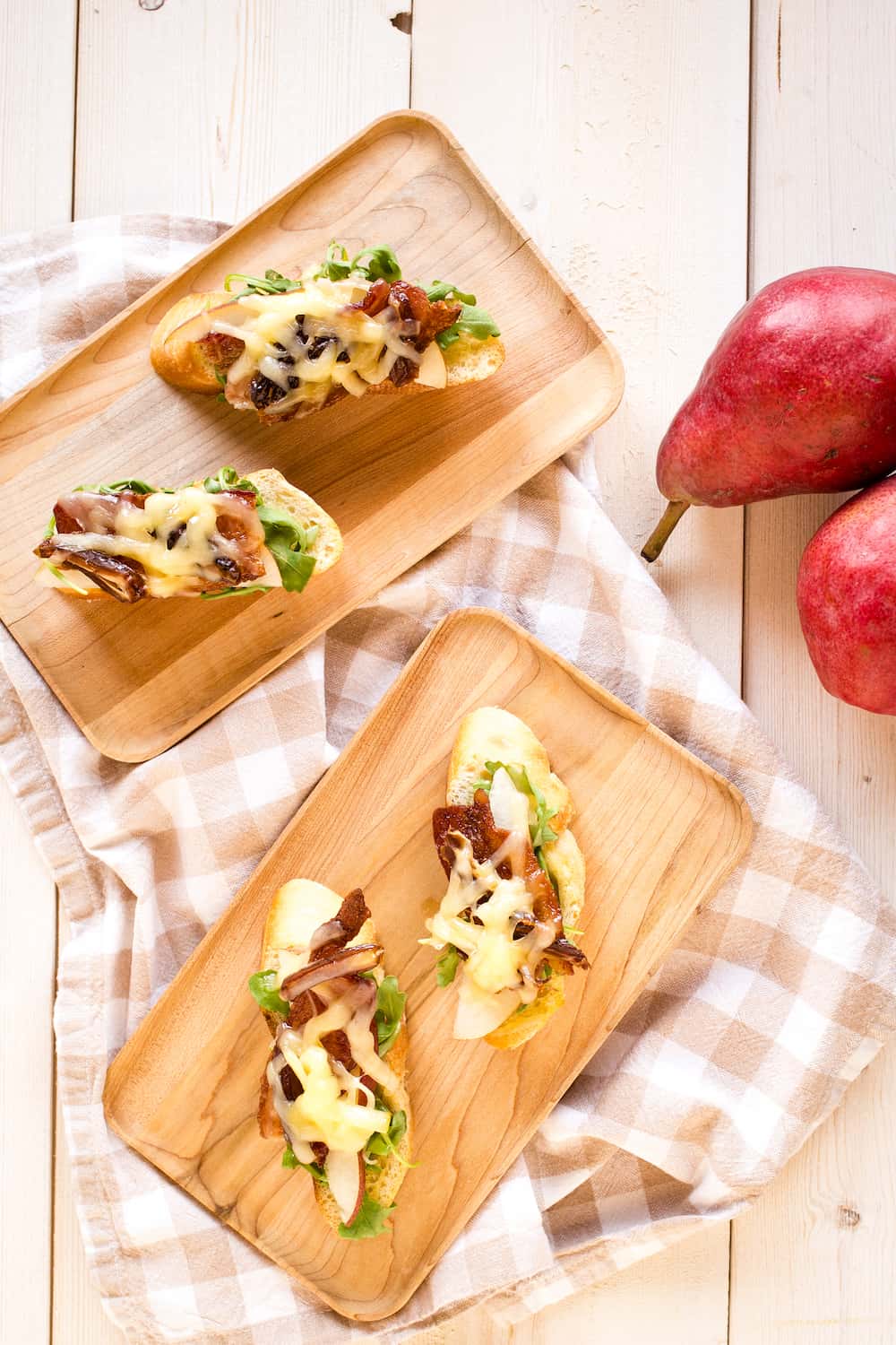 tartines topped with arugula, bacon, pears, dates, and cheese
